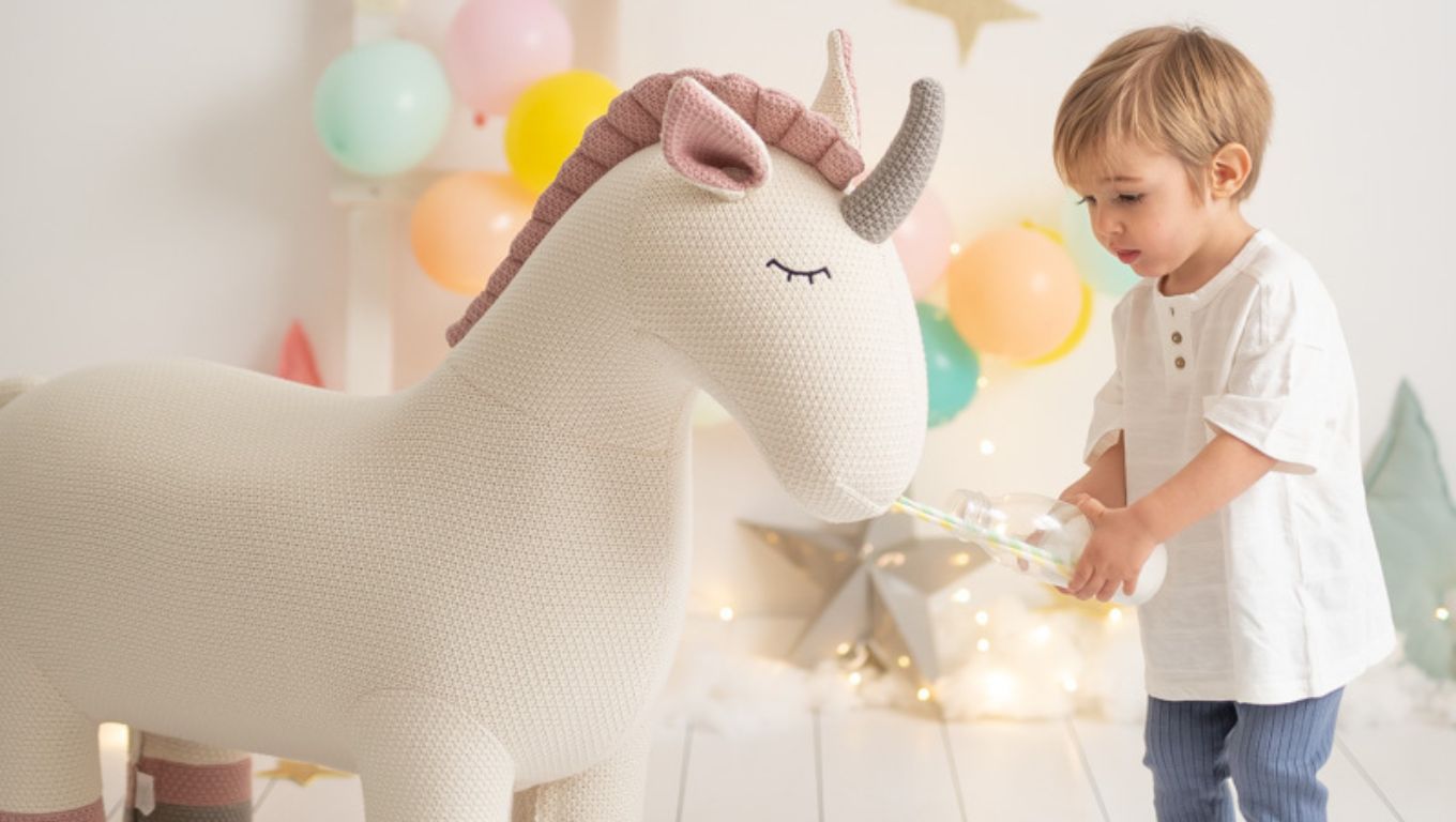 Amigurumi gigante de unicornio con niño jugando